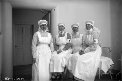 Fyra sjuksköterskor, operationssköterskor. Sjukvårdsmiljö; behandlingsrum.