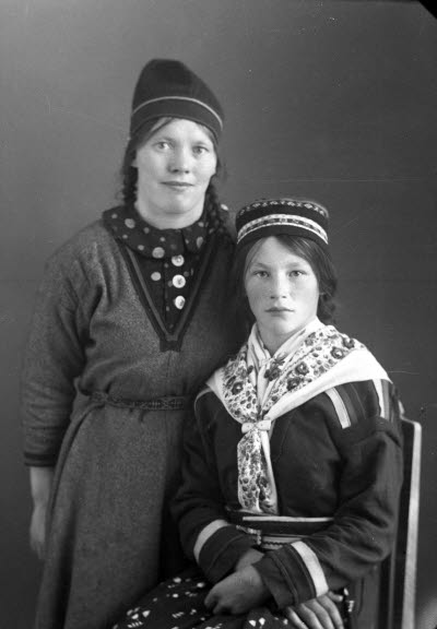 Porträtt av två damer i samedräkter. Ateljefoto.