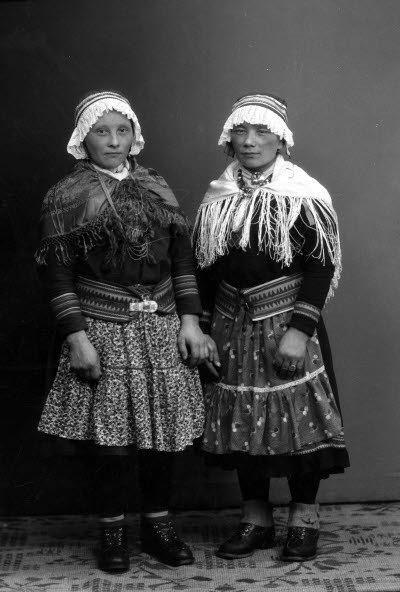 Porträtt av två damer i samedräkter. Ateljefoto.