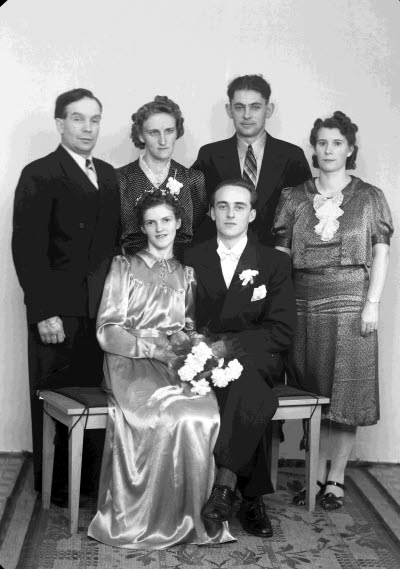 Porträtt av ett brudpar samt två herrar och två damer. Ateljefoto.