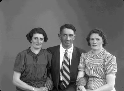 Porträtt av en herre och två damer. Ateljefoto.