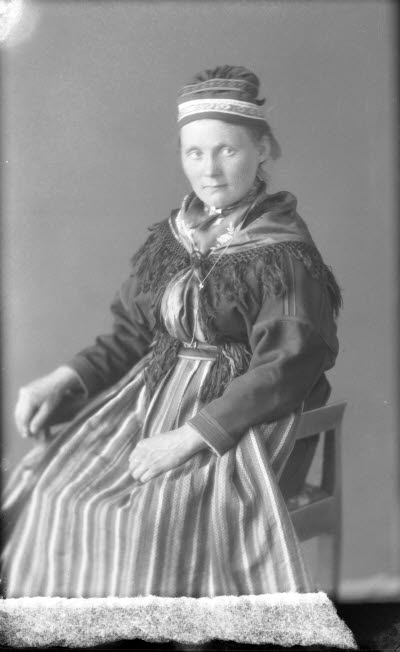 Porträtt av en dam i samedräkt. Ateljefoto.