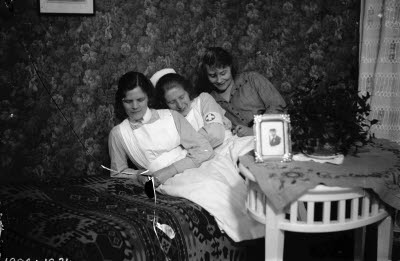 Interiör; tre damer (två i sjuksköterskeuniform). Oidentifierade.