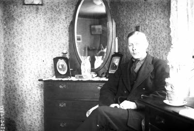 En herre i hemmiljö; pigtittare, spegelbyrå.