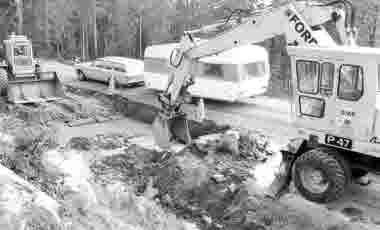 Vägarbete. Traktor, hjulgrävare; grävskopa, personbil med husvagn.