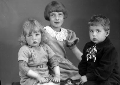 Porträtt av tre barn; två flickor och en pojke. Ateljefoto.