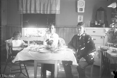 Ett par och ett barn. Hemmiljö; kök, köksbord, pinnsoffa, pigtittare.