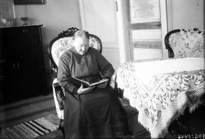 Äldre dam i hemmiljö. Vardagsrum. Högreståndsmiljö.