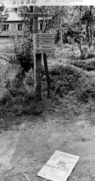 Skyltning efter Kungsleden. På marken intill, ett exemplar av morgontidningen Norrbottens Kuriren.