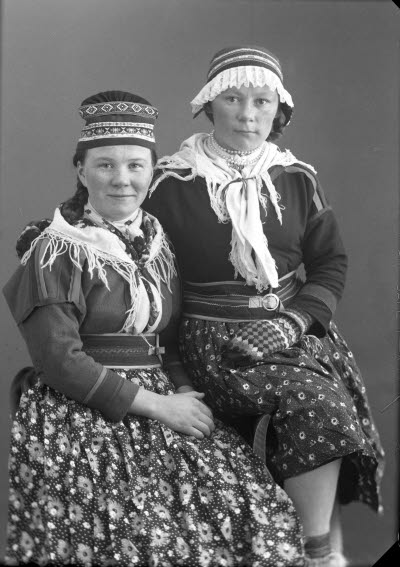 Porträtt av två damer i samedräkter. Ateljefoto.