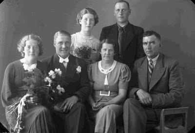 Porträtt av ett brudpar samt två herrar och två damer. Ateljefoto.