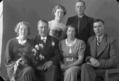 Porträtt av ett brudpar samt två herrar och två damer. Ateljefoto.