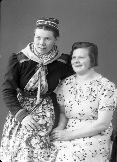 Porträtt av två damer, varav en i samedräkt. Ateljefoto.