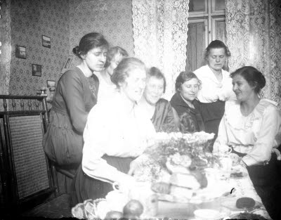 Hemmiljö; interiör, vardagsrum. Sju damer vid dukat kaffebord. Oidentifierade.