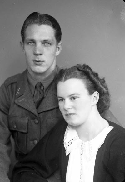 Porträtt av ett par; en herre i militäruniform och en dam. Ateljefoto.