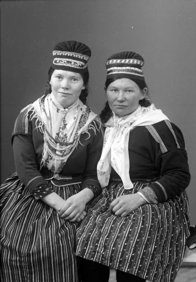 Porträtt av två damer i samedräkter. Ateljefoto.