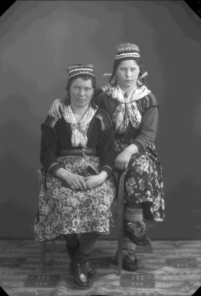 Porträtt av två damer i samedräkter. Ateljefoto.