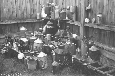 Interiör: Polisens förråd av beslagtagna hembränningsapparater; brännvin; lönnkrögeri.