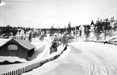 Vägen till Bolagsområdet med järnvägsbron. I bakgrunden Johannes. Disponentvillan och Bolagskontoret, LKAB kontor. Vintermotiv.
