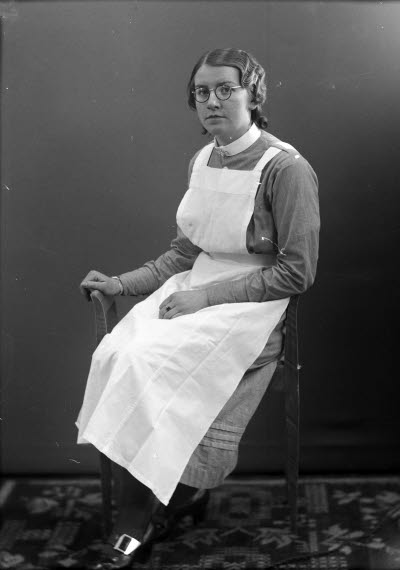 Porträtt av en dam i sköterskeuniform. Ateljefoto.