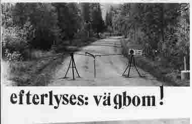 Provisorisk vägbom; kedja, stativ. Skylt: "In- och utfart". Skogsbilväg.