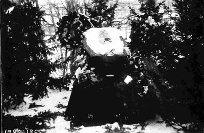 Öppen kista; blomdekoration. En herre; oidentifierad.