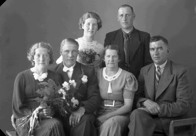 Porträtt av ett brudpar samt två herrar och två damer. Ateljefoto.