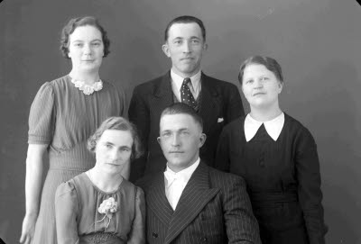 Porträtt av ett brudpar samt en herre och två damer. Ateljefoto.