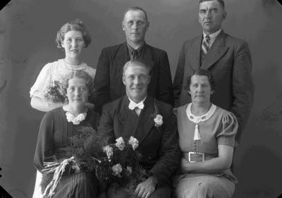 Porträtt av ett brudpar samt två damer och två herrar. Ateljefoto.