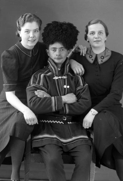 Porträtt av en herre i samedräkt och två damer. Ateljefoto.