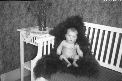 Ett barn. Hemmiljö; vardagsrum. Skinnfäll.