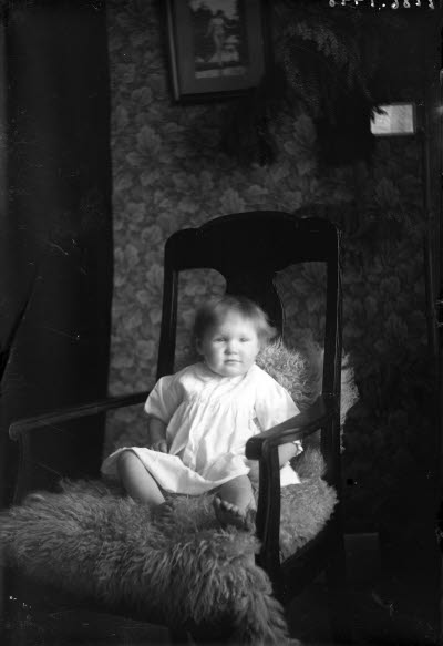 Ett barn. Liten flicka i hemmiljö. Vardagsrum.