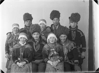 Porträtt av nio personer i samedräkter, gruppfoto.