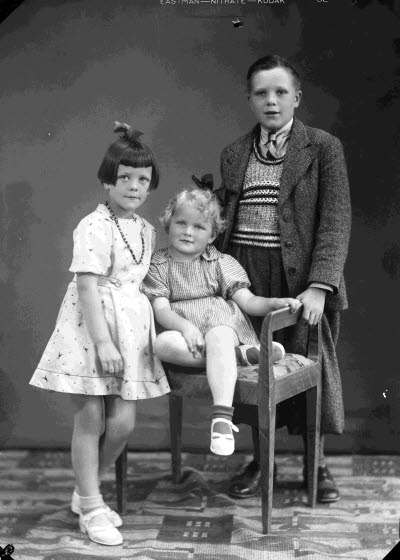 Porträtt av tre barn, två flickor och en pojke. Ateljefoto.