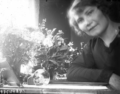 En dam. Självporträtt av fotografen Ida Barrel. Hemmiljö.