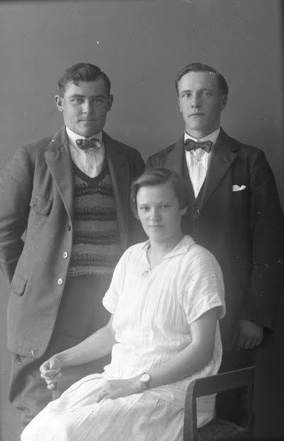 Porträtt av två herrar och en dam. Ateljefoto.