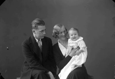 Porträtt av familj; en herre och en dam med ett barn. Ateljefoto.