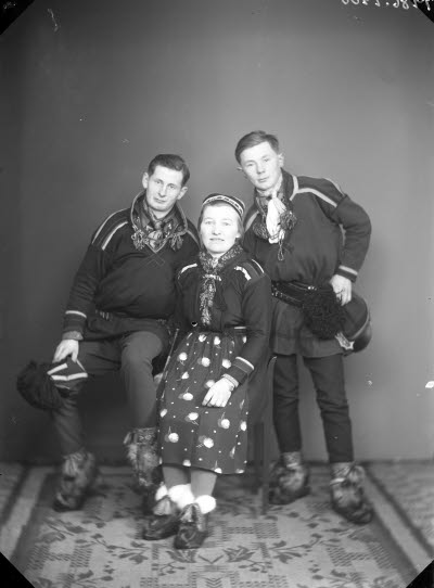 Porträtt av två herrar och en dam i samedräkter. Ateljefoto.