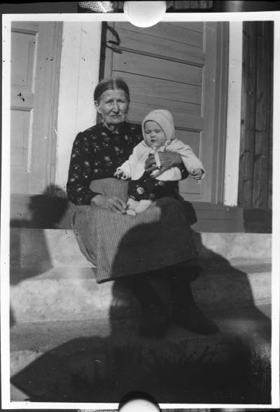 Porträtt av en äldre dam med ett barn i famnen.