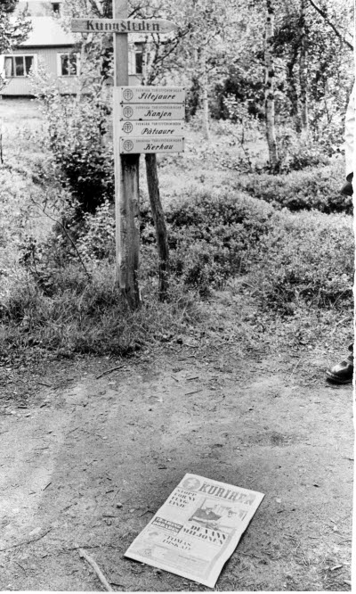 Skyltning efter Kungsleden. På marken intill, ett exemplar av morgontidningen Norrbottens Kuriren.