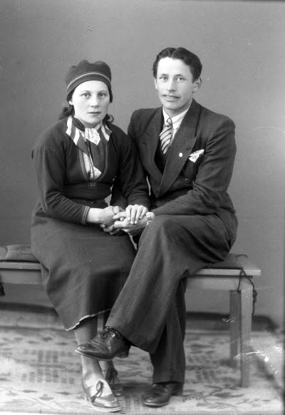 Porträtt av ett par; dam i samedräkt. Ateljefoto.