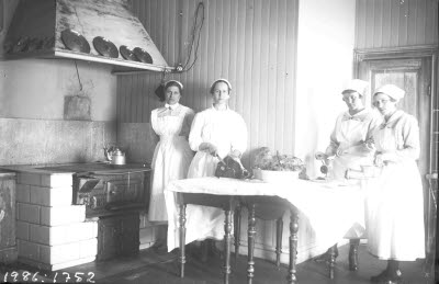 Gruppbild: matlagning; kokerskor i arbete. Interiör: kök. Möjligen sjukhuset eller Kaptensgårdens sanatorium. Oidentifierade.
