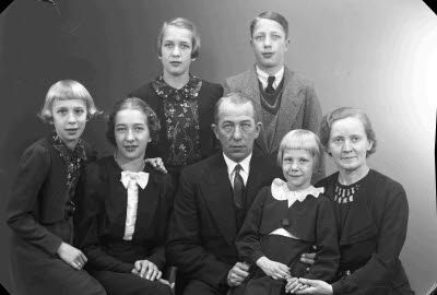 Porträtt av en herre och en dam med fem barn; flickor, pojke. Ateljefoto.