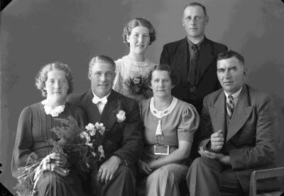 Porträtt av ett brudpar samt två herrar och två damer. Ateljefoto.