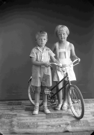 Porträtt av två barn med en cykel. Pojke och flicka. Ateljefoto.