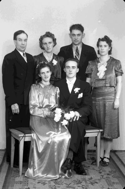 Porträtt av ett brudpar samt två herrar och två damer. Ateljefoto.