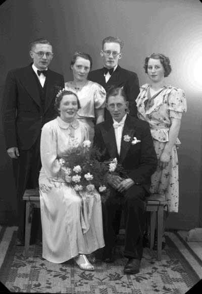 Porträtt av ett brudpar samt två herrar och två damer. Ateljefoto.