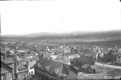 Vy över södra Malmberget med bl. a. Tingvallsgatan/Skolgatan; Wiklunds Pappershandel, begravningsbyrån, Kallemans hus och affär.