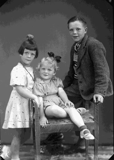 Porträtt av tre barn, två flickor och en pojke. Ateljefoto.