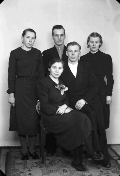 Porträtt av ett brudpar samt två herrar och en dam. Ateljefoto.